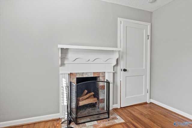 interior details featuring a tiled fireplace and hardwood / wood-style flooring