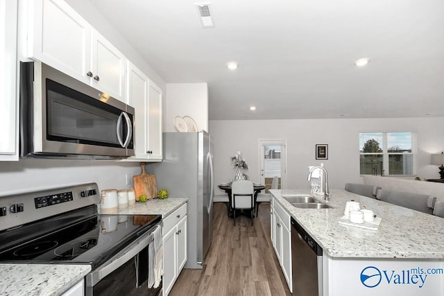 kitchen with stainless steel appliances, a sink, white cabinets, light wood finished floors, and recessed lighting