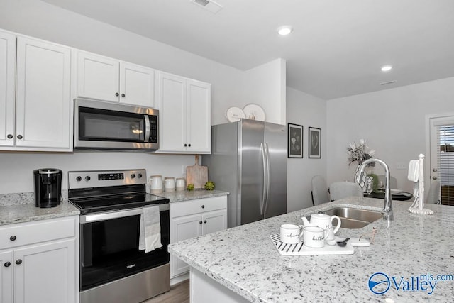 kitchen featuring appliances with stainless steel finishes, a sink, white cabinets, and recessed lighting