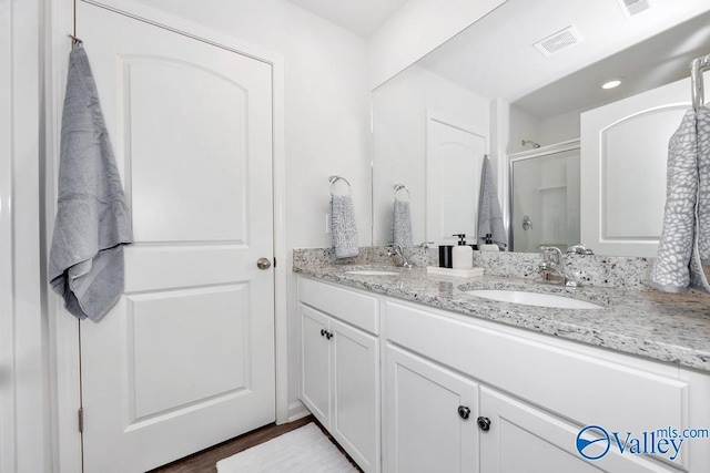 full bath featuring a stall shower, double vanity, recessed lighting, and wood finished floors