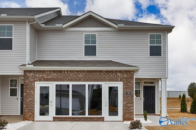 rear view of property featuring french doors, brick siding, and a shingled roof