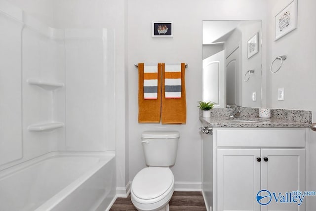 full bathroom featuring baseboards, toilet, vanity, wood finished floors, and washtub / shower combination