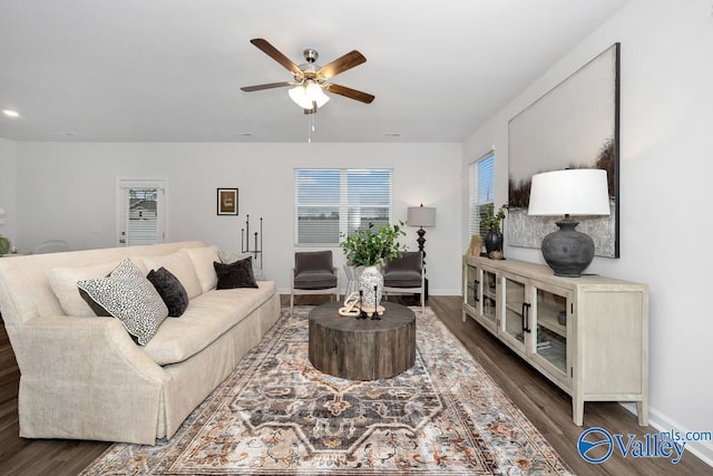 living area featuring dark wood-style flooring, a ceiling fan, and baseboards