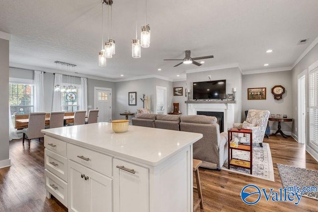 kitchen with dark hardwood / wood-style flooring, a kitchen island, hanging light fixtures, and white cabinets