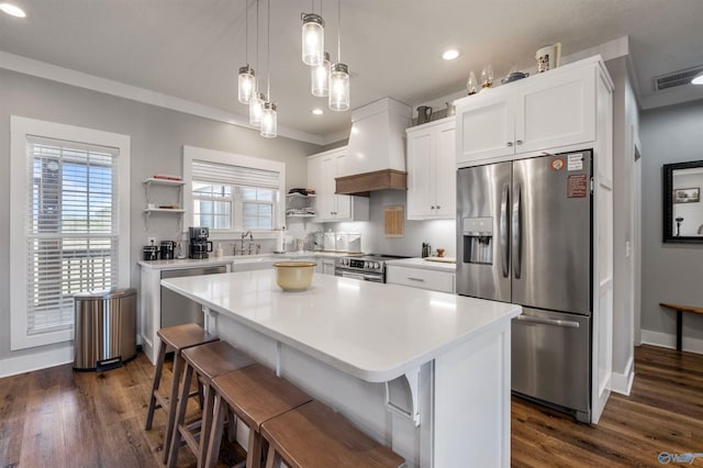 kitchen with dark wood-type flooring, a center island, white cabinets, a kitchen breakfast bar, and appliances with stainless steel finishes