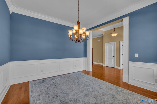 unfurnished room with an inviting chandelier, hardwood / wood-style floors, and crown molding