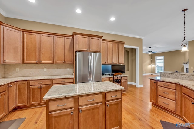 kitchen with light wood-type flooring, ceiling fan, decorative light fixtures, and stainless steel fridge