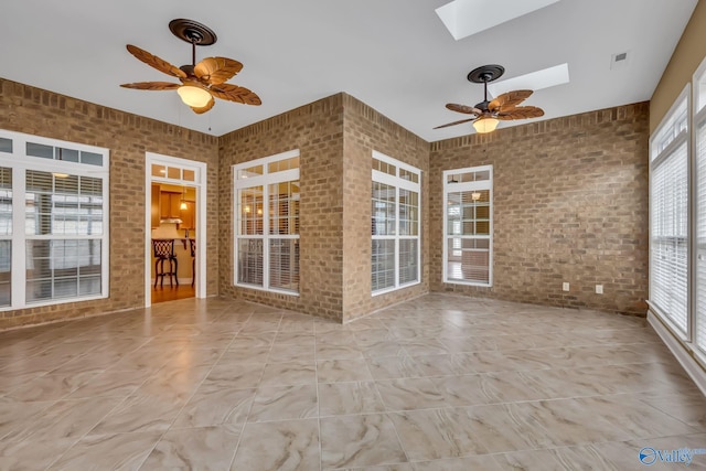 unfurnished sunroom featuring ceiling fan and a skylight