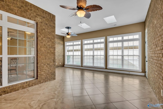 unfurnished sunroom with ceiling fan, a skylight, and a healthy amount of sunlight