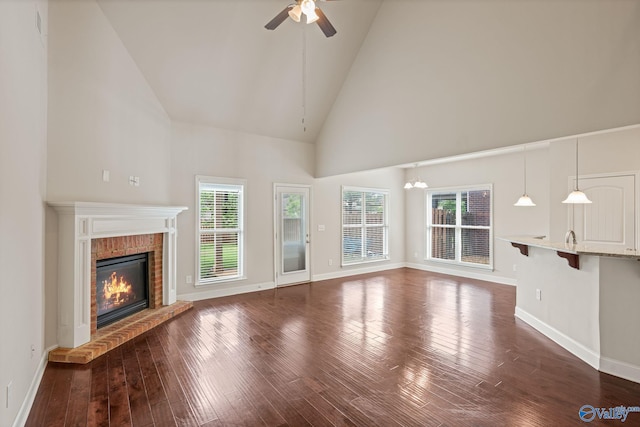 unfurnished living room with plenty of natural light, baseboards, a fireplace, and high vaulted ceiling
