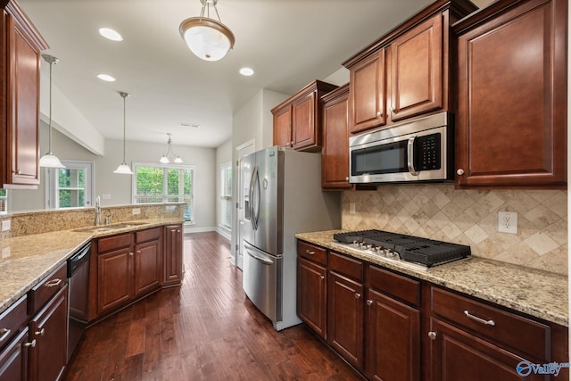 kitchen featuring backsplash, pendant lighting, appliances with stainless steel finishes, a sink, and dark wood-style floors