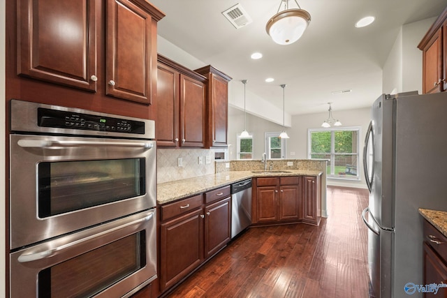 kitchen featuring a sink, dark wood finished floors, stainless steel appliances, a peninsula, and visible vents