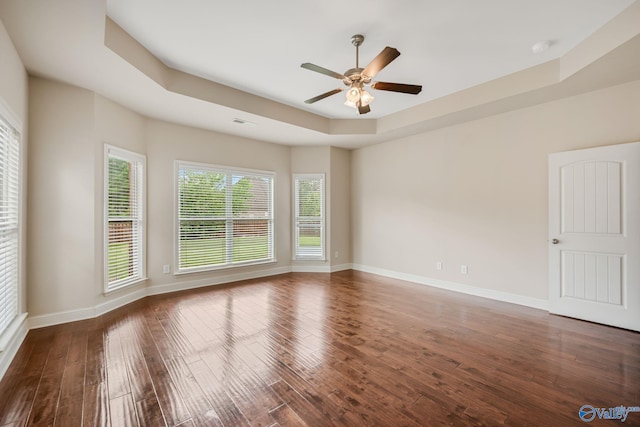 unfurnished room featuring baseboards, a ceiling fan, a tray ceiling, and wood finished floors