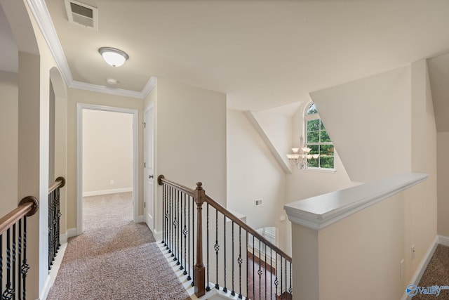 hallway with carpet floors, visible vents, baseboards, and an upstairs landing