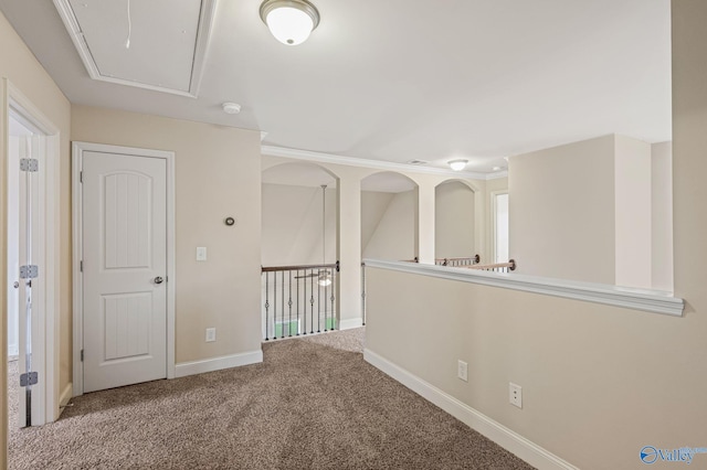 carpeted empty room featuring baseboards and attic access