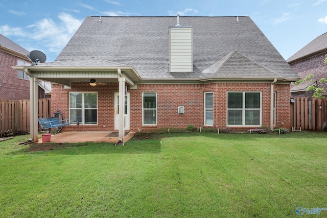 rear view of house with brick siding, ceiling fan, a fenced backyard, a patio area, and a lawn