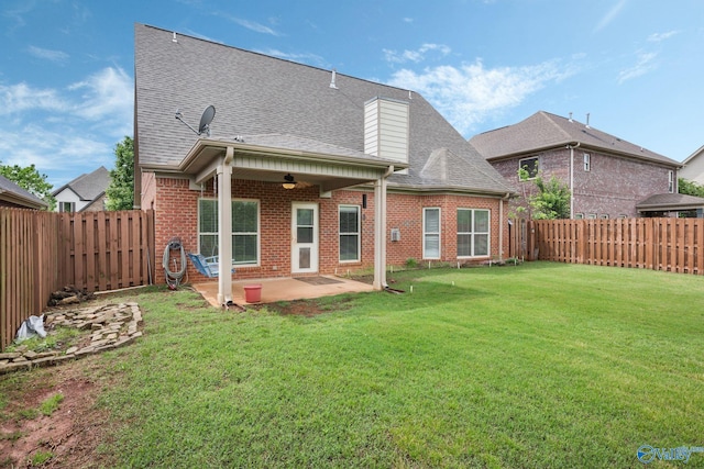rear view of house featuring a shingled roof, brick siding, ceiling fan, a fenced backyard, and a patio