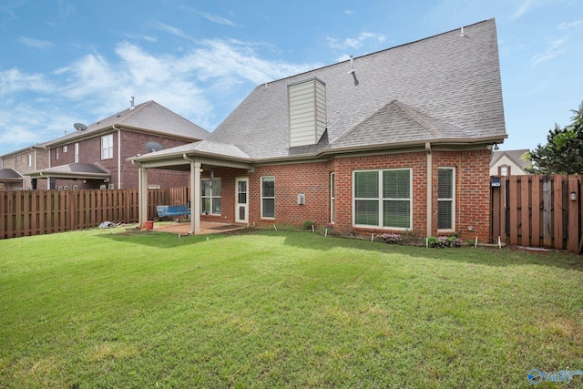 rear view of property with brick siding, a fenced backyard, roof with shingles, and a patio