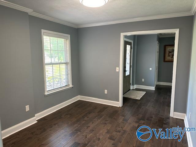 spare room with ornamental molding, dark wood finished floors, and baseboards