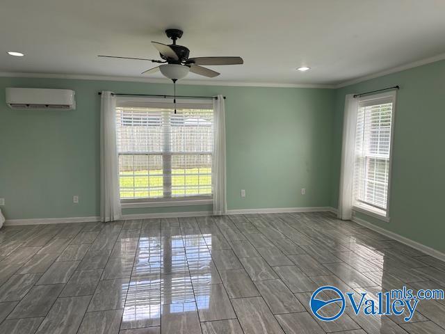 spare room with a wealth of natural light, crown molding, and an AC wall unit