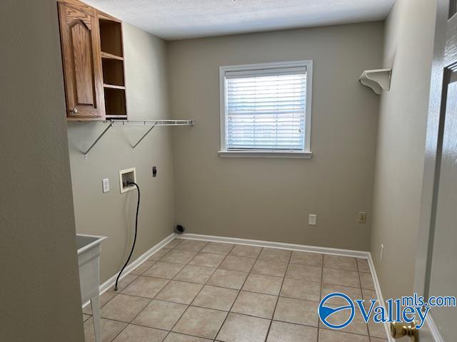 laundry area with cabinet space, light tile patterned floors, baseboards, hookup for a washing machine, and hookup for an electric dryer