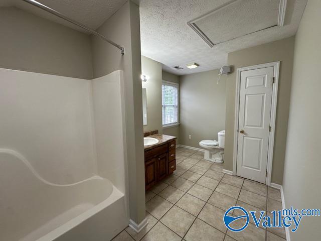 full bath with tile patterned floors, baseboards, a textured ceiling, and toilet