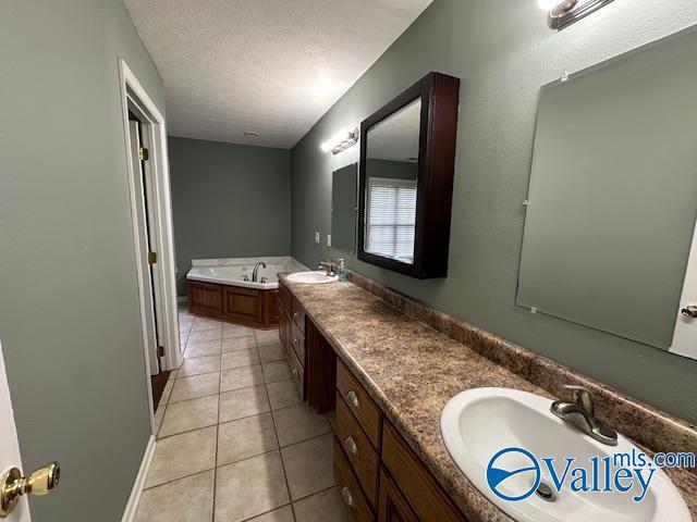 bathroom featuring a bath, tile patterned floors, a sink, and double vanity