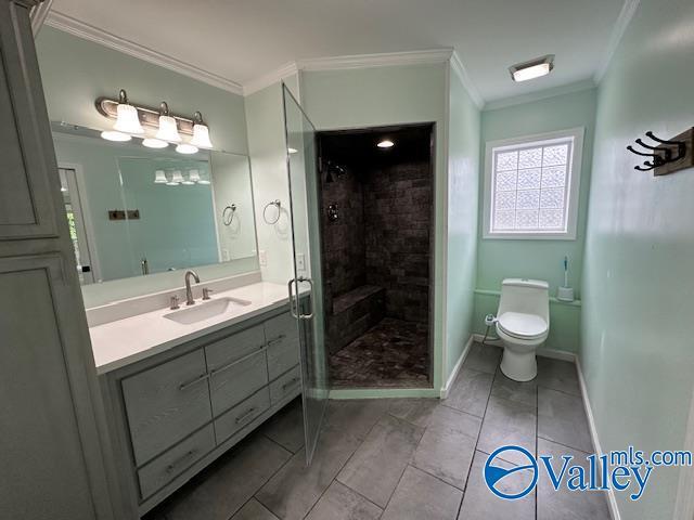 full bath featuring a shower stall, toilet, vanity, crown molding, and baseboards