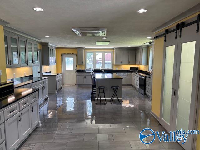 kitchen featuring glass insert cabinets, dark countertops, a center island, and range