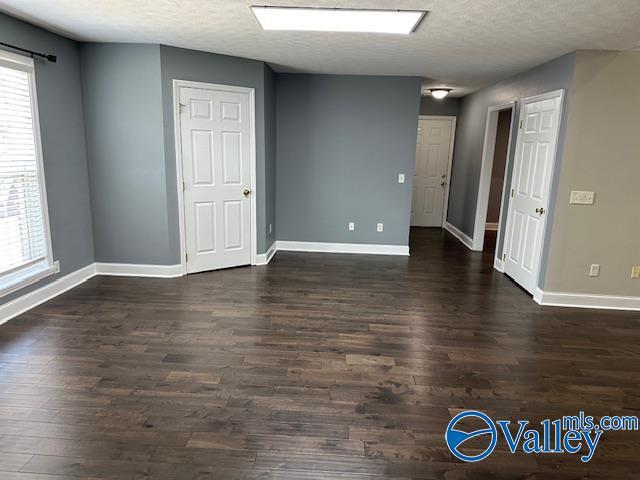 spare room with dark wood-type flooring, a textured ceiling, and baseboards