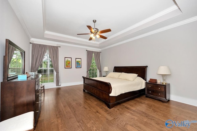 bedroom with hardwood / wood-style flooring, ceiling fan, crown molding, and a raised ceiling