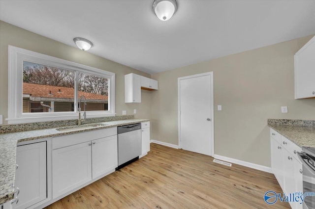 kitchen with light stone counters, stainless steel dishwasher, light wood-style floors, white cabinetry, and a sink