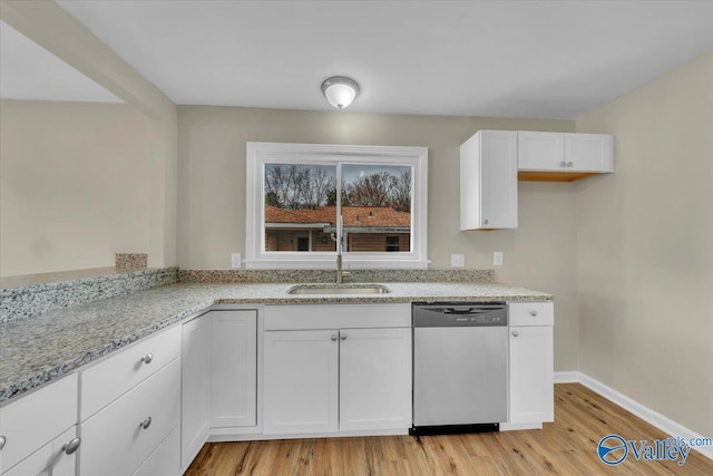 kitchen with light stone counters, a sink, white cabinets, light wood-type flooring, and dishwasher