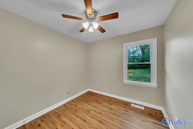 unfurnished room with a ceiling fan, visible vents, light wood finished floors, and baseboards