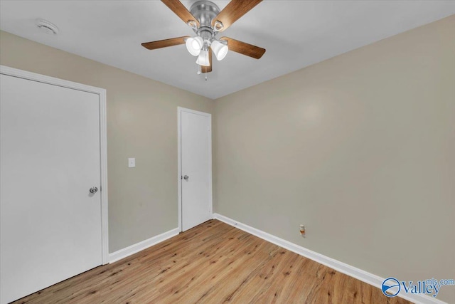 spare room featuring ceiling fan, light wood finished floors, and baseboards