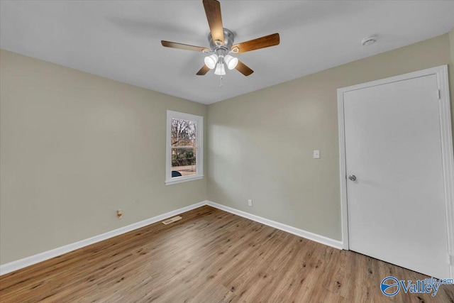 unfurnished room featuring a ceiling fan, visible vents, baseboards, and wood finished floors