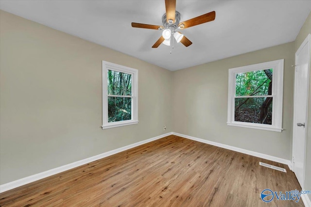 spare room featuring a ceiling fan, baseboards, visible vents, and wood finished floors