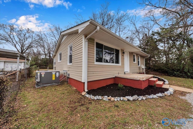 view of side of property with a yard, fence, and central AC unit