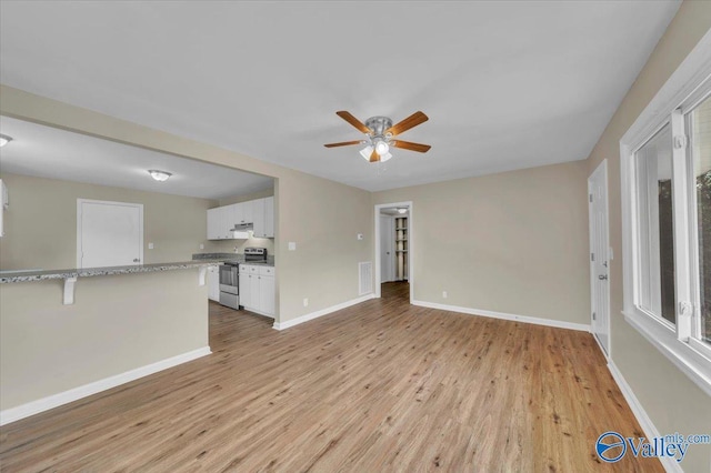 unfurnished living room with visible vents, a ceiling fan, light wood-style flooring, and baseboards