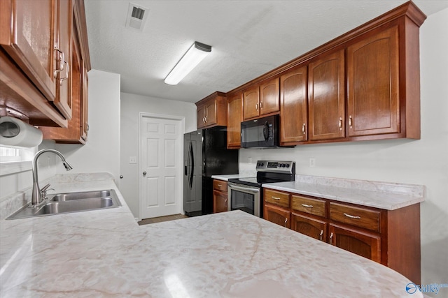 kitchen featuring light stone countertops, a textured ceiling, sink, and black appliances