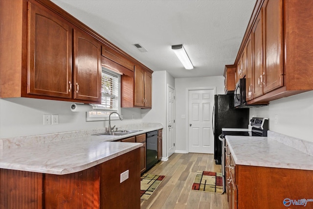 kitchen featuring light hardwood / wood-style floors, kitchen peninsula, black appliances, a textured ceiling, and sink