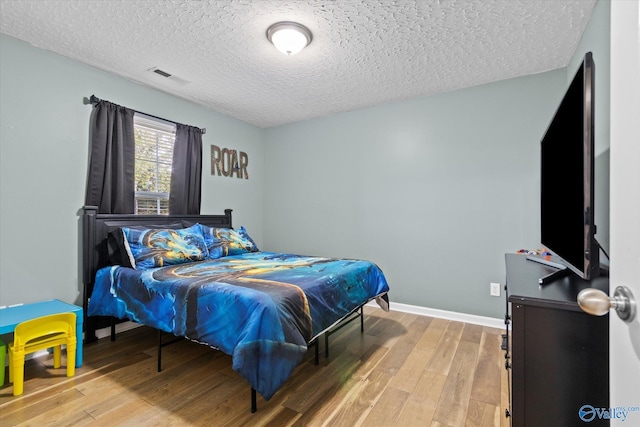 bedroom featuring hardwood / wood-style floors and a textured ceiling