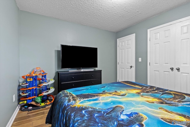 bedroom with a closet, a textured ceiling, and hardwood / wood-style flooring