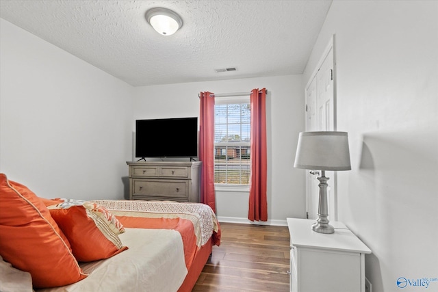 bedroom featuring dark wood-type flooring and a textured ceiling