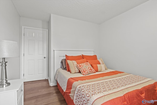 bedroom with a textured ceiling and dark hardwood / wood-style floors