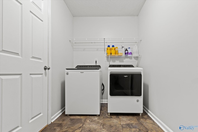 laundry area with a textured ceiling and washer and dryer