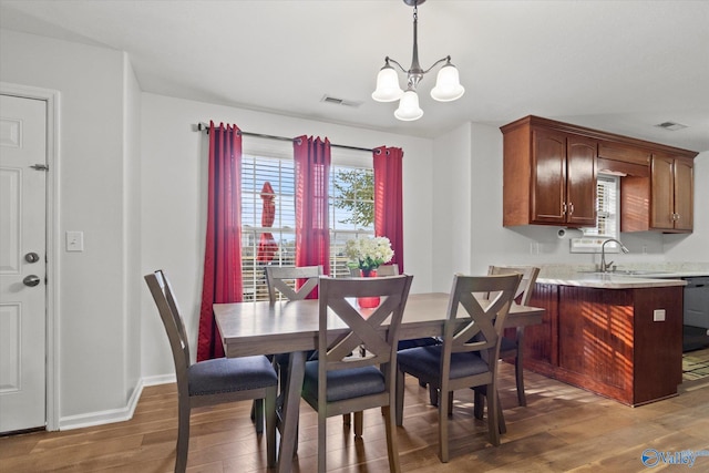 dining area with hardwood / wood-style floors, sink, and an inviting chandelier