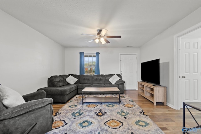 living room featuring a textured ceiling, hardwood / wood-style flooring, and ceiling fan