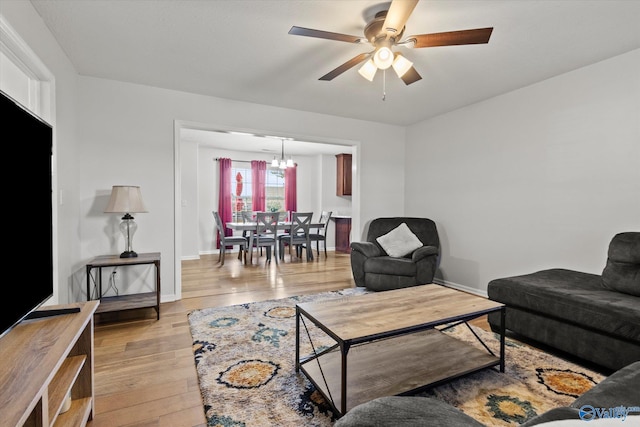 living room featuring light hardwood / wood-style floors and ceiling fan with notable chandelier