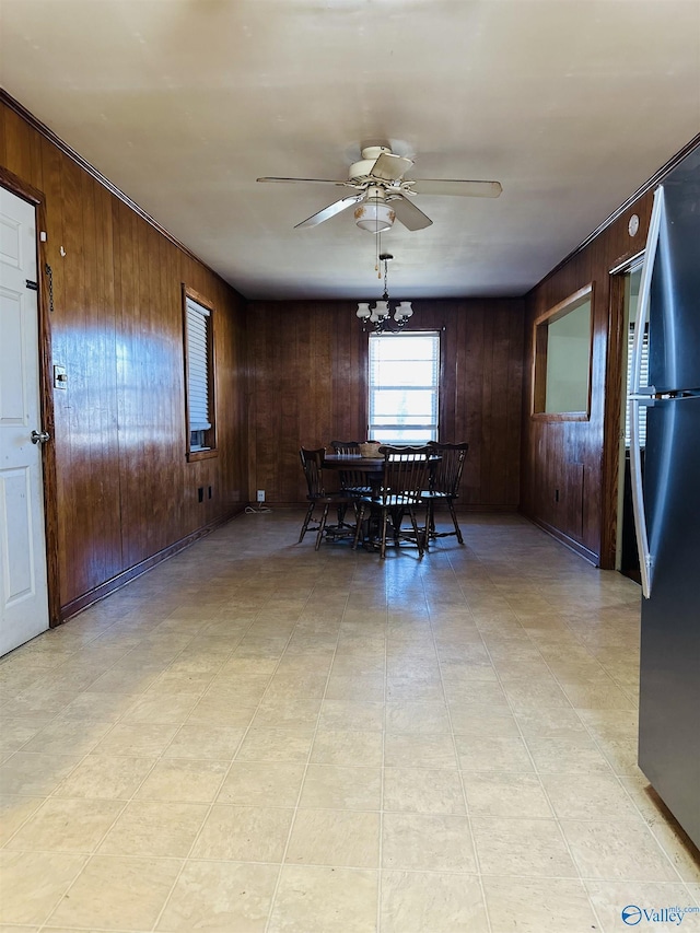 unfurnished dining area with ceiling fan with notable chandelier and wooden walls